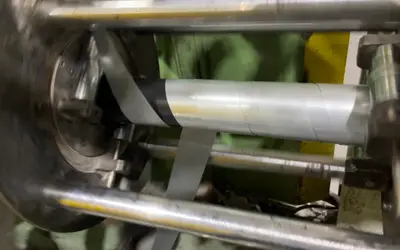 Nastro metallico avvolto a spirale attorno a un cavo nella nastratrice